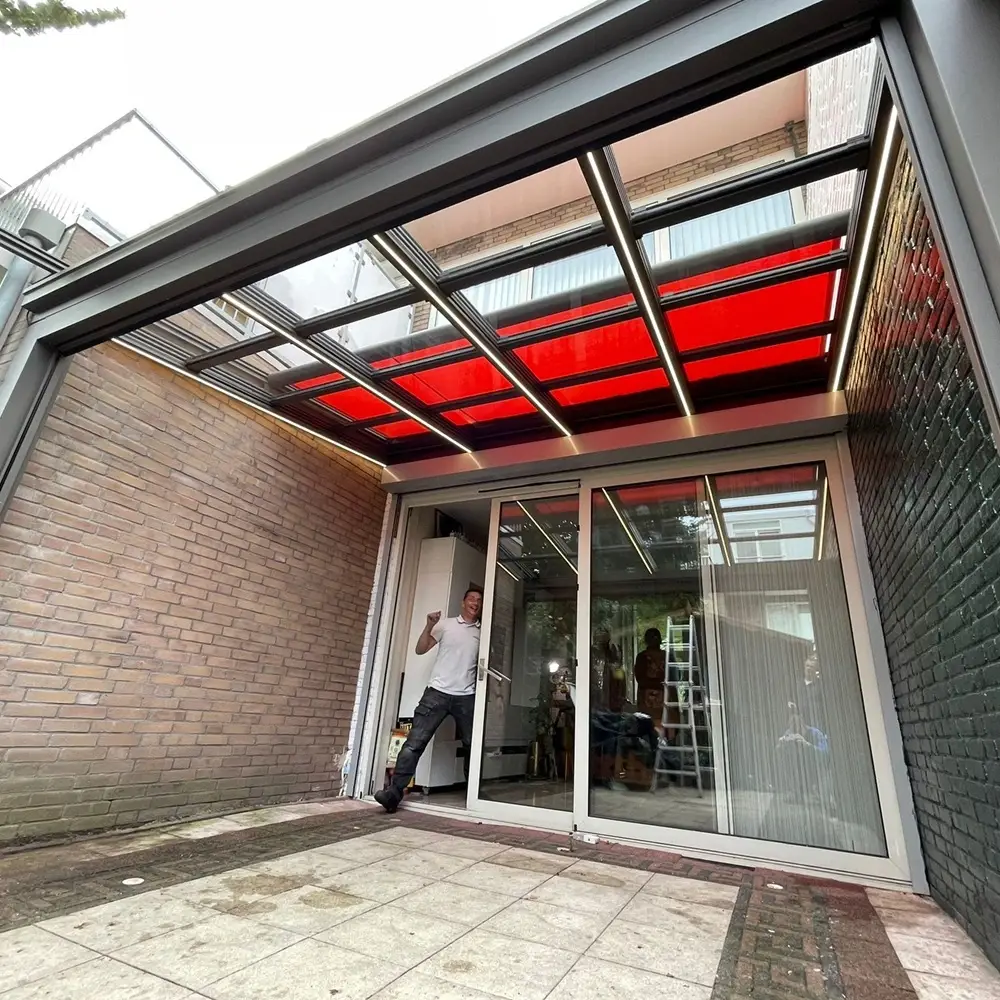 Schuifbaar glazen dak met rode zonwering geplaatst door Veldman Zonwering in Amsterdam