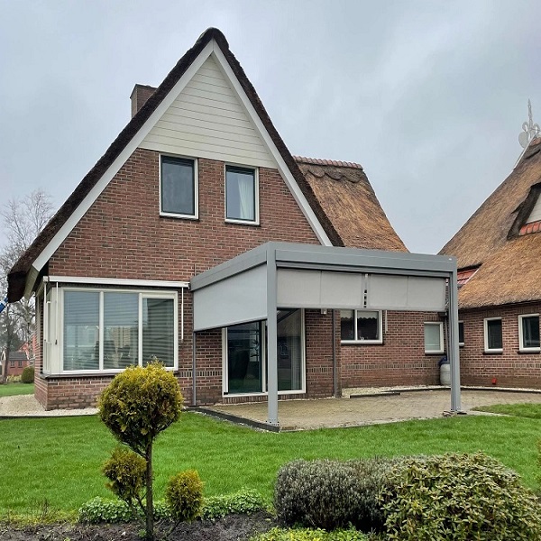 Huis met rieten dak en moderne grijze terrasoverkapping