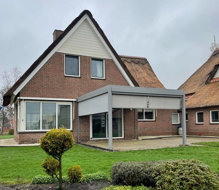 Huis met rieten dak en moderne grijze terrasoverkapping