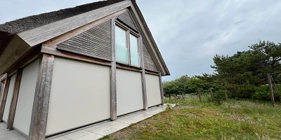 Exterieur van een woning met gesloten screens tegen een natuurlijke actergrond Exterieur van een woning met gesloten screens tegen een natuurlijke actergrond