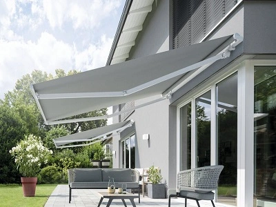 Grijs knikarmscherm uitgeschoven boven modern terras Grijs knikarmscherm uitgeschoven boven modern terras