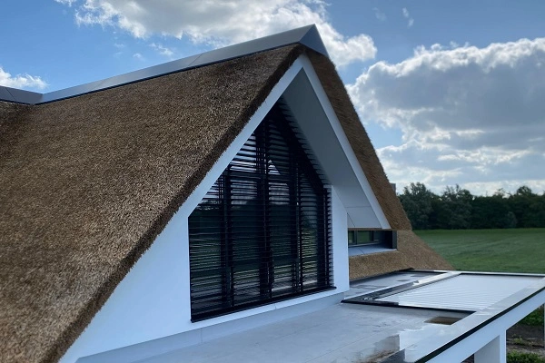 Modern huis met rieten dak en grote ramen in een landelijke omgeving Modern huis met rieten dak en grote ramen in een landelijke omgeving