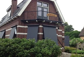 Traditioneel huis met zwart-grijze uitvalschermen aan de ramen