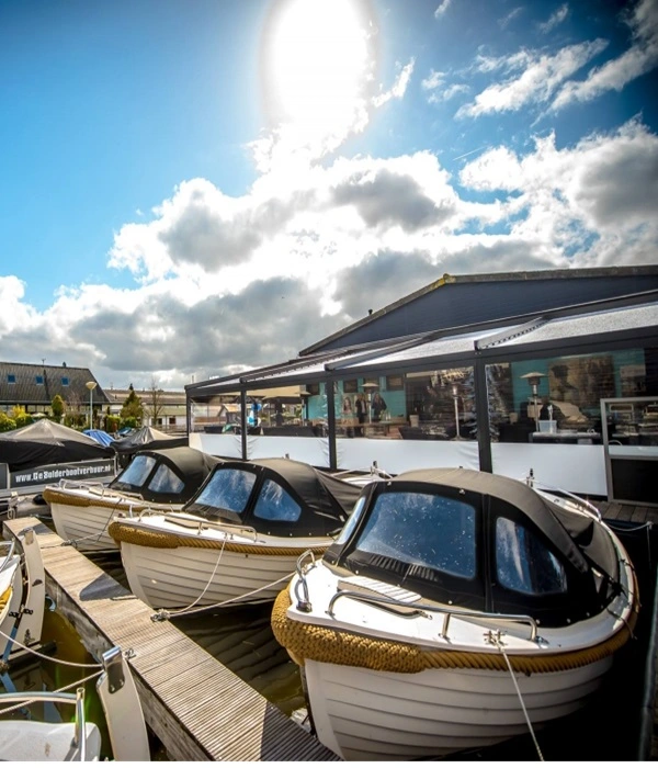 Barcafé aan het water met een overkapping en aangemeerde boten op een zonnige dag Barcafé aan het water met een overkapping en aangemeerde boten op een zonnige dag