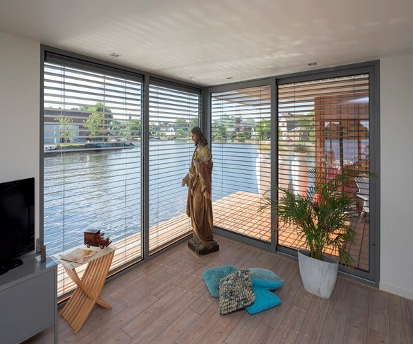 Binnenruimte met grote ramen en jaloezieën, uitkijkend over een waterrijk gebied Binnenruimte met grote ramen en jaloezieën, uitkijkend over een waterrijk gebied