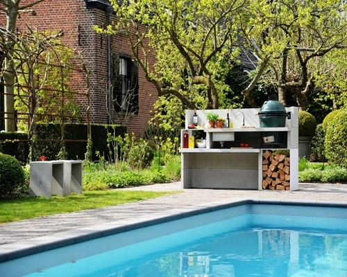 Buitenkeuken naast zwembad in een groene tuin met bomen Buitenkeuken naast zwembad in een groene tuin met bomen