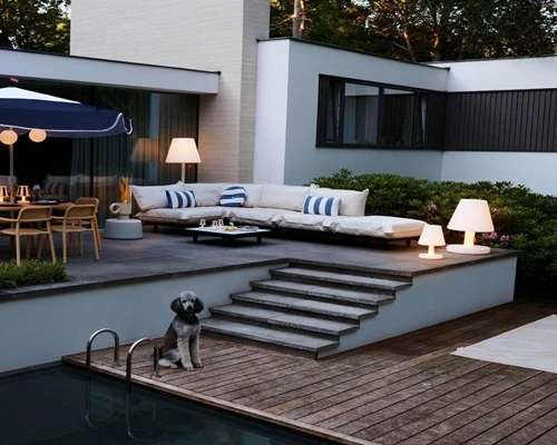 Buitenruimte met grijze lounge bank, blauw-wit gestreepte kussens, en een hond Buitenruimte met grijze lounge bank, blauw-wit gestreepte kussens, en een hond