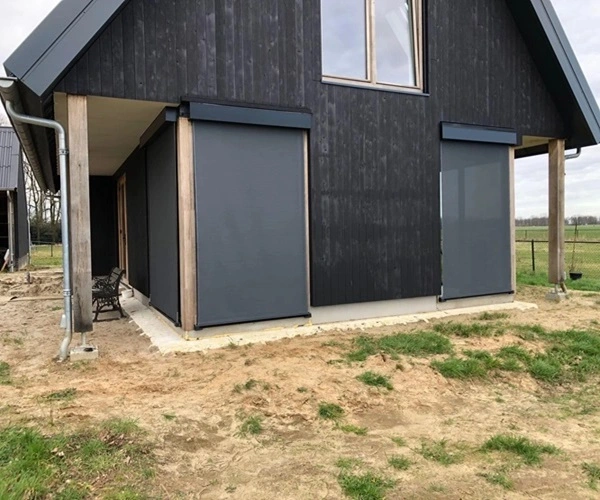 Houten woning, met grijze screens die de ramen bedekken om zonlicht te beheersen Houten woning, met grijze screens die de ramen bedekken om zonlicht te beheersen