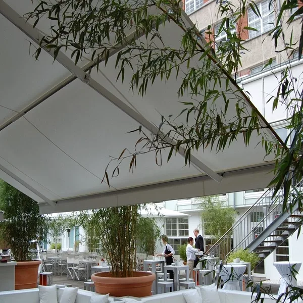 Terras van een ijssalon met witte meubels onder een grote uittrekbare zonwering