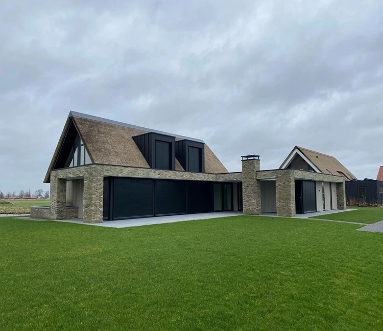 Villa met rieten dak en grote ramen, voorzien van zonwering