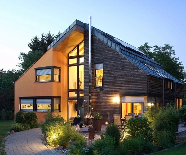 Woning met houten en oranje gevels, grote ramen met rolluiken en een verlichte tuin Woning met houten en oranje gevels, grote ramen met rolluiken en een verlichte tuin