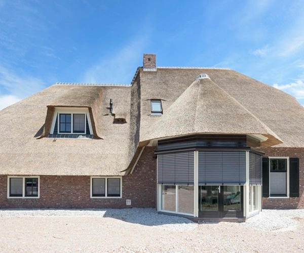 Woning met rieten dak en buitenjaloezieën in antraciet kleur Woning met rieten dak en buitenjaloezieën in antraciet kleur