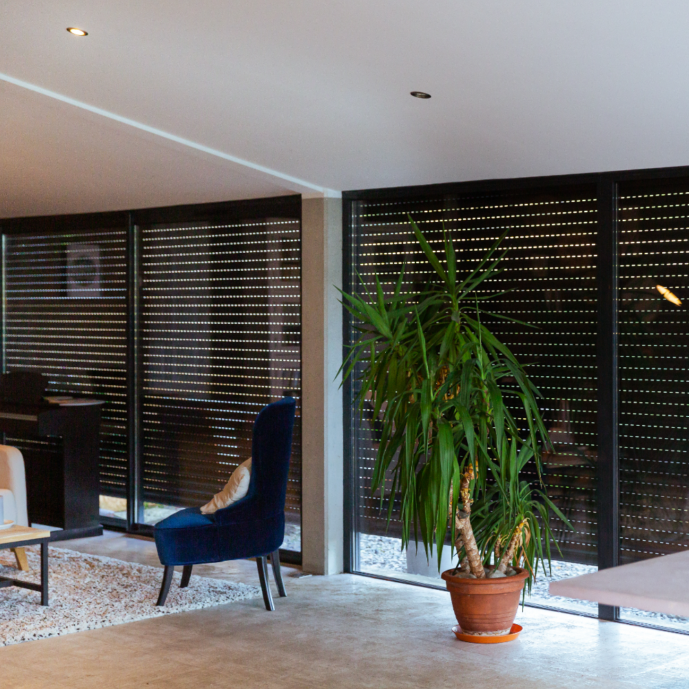 Woonkamer voorzien van zwarte rolluiken Woonkamer voorzien van zwarte rolluiken