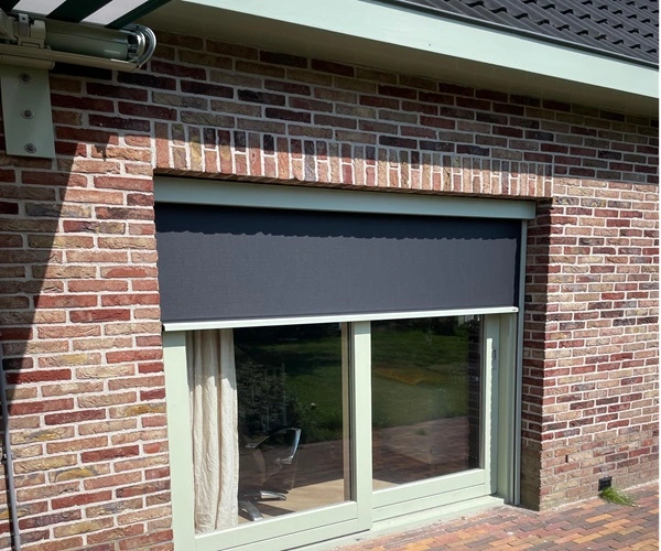 Zipscreen in antraciet kleur geïnstalleerd voor een raam van een huis met bakstenen muur. Zipscreen in antraciet kleur geïnstalleerd voor een raam van een huis met bakstenen muur.