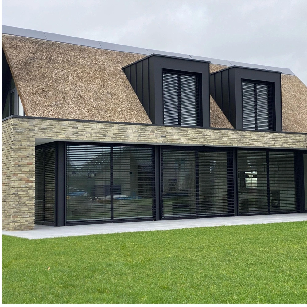 Buitenjaloezie raffstore bij woning met rieten dak en grote ramen