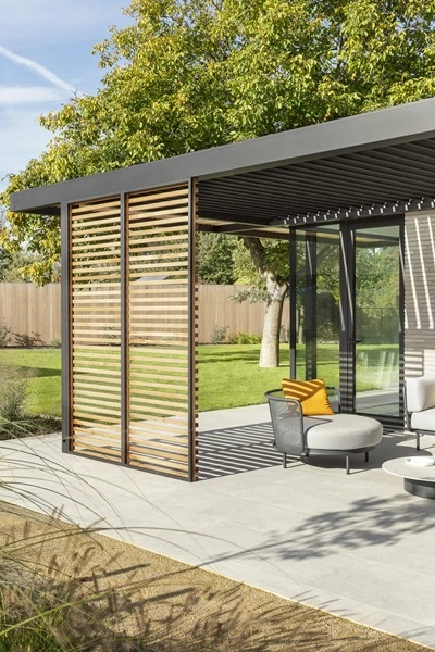 Hout en aluminium lamellenoverkapping in een groene tuin Hout en aluminium lamellenoverkapping in een groene tuin