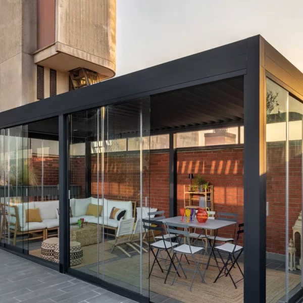 Lamellen overkapping joy met glazen schuifdeuren naast een zitgedeelte en eettafel Lamellen overkapping joy met glazen schuifdeuren naast een zitgedeelte en eettafel