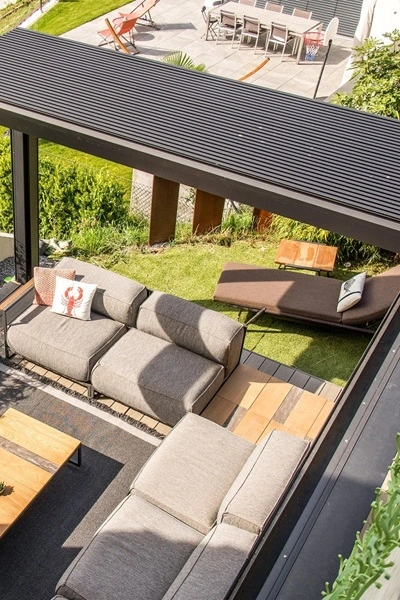 Open Lamellendak Brera over een loungeset met tuinzicht Open Lamellendak Brera over een loungeset met tuinzicht