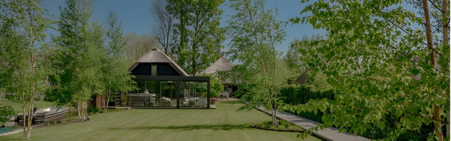 Panoramisch uitzicht op tuinkamer met lamellen overkapping, rieten dakhuizen