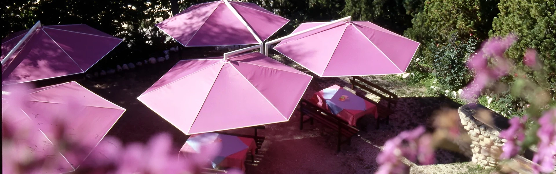 Parasol Rialto in roze uitvoering boven picknicktafels in bergachtige omgeving (1)