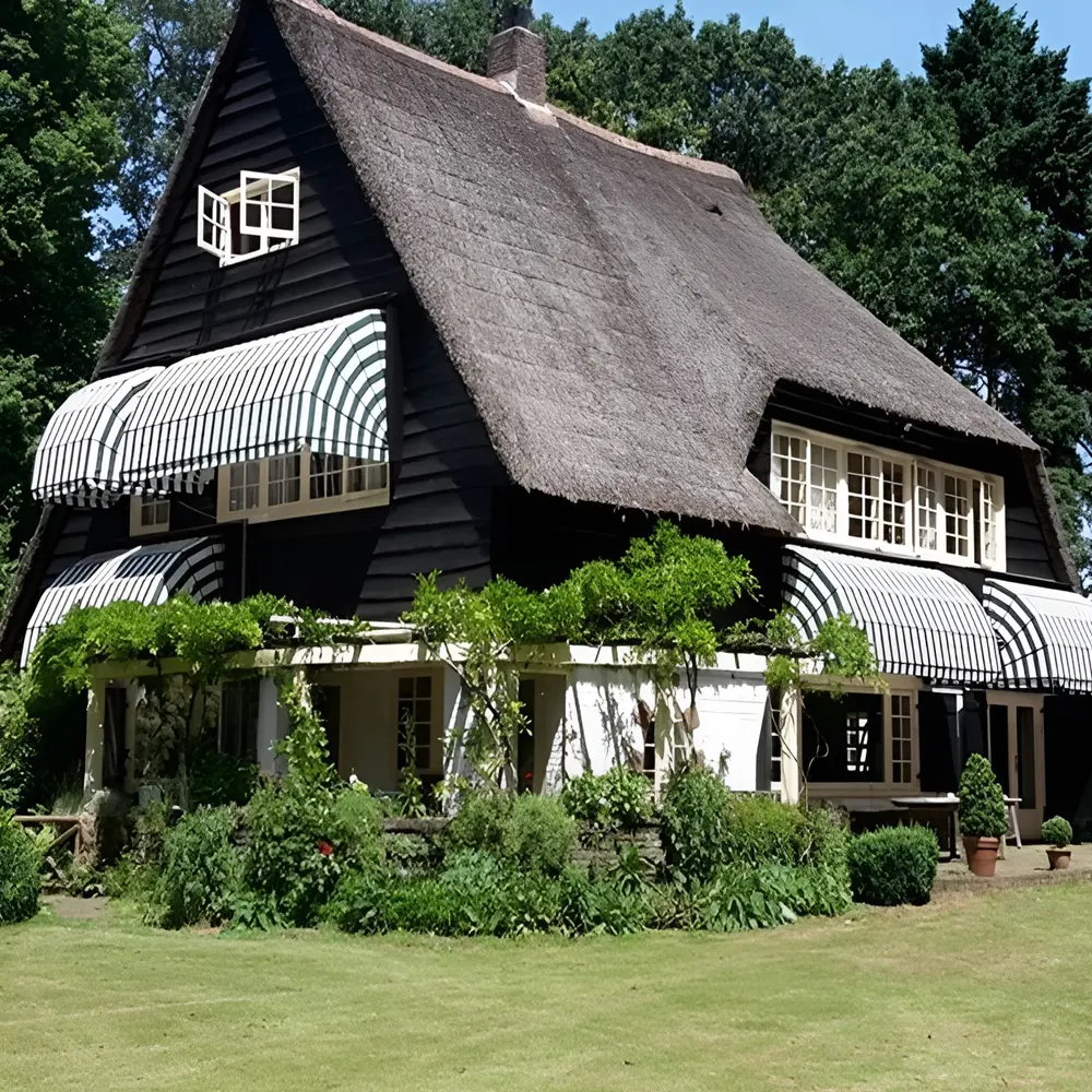 Bakstenen huis met groen-wit gestreepte aluminium markiezen rondom de ramen
