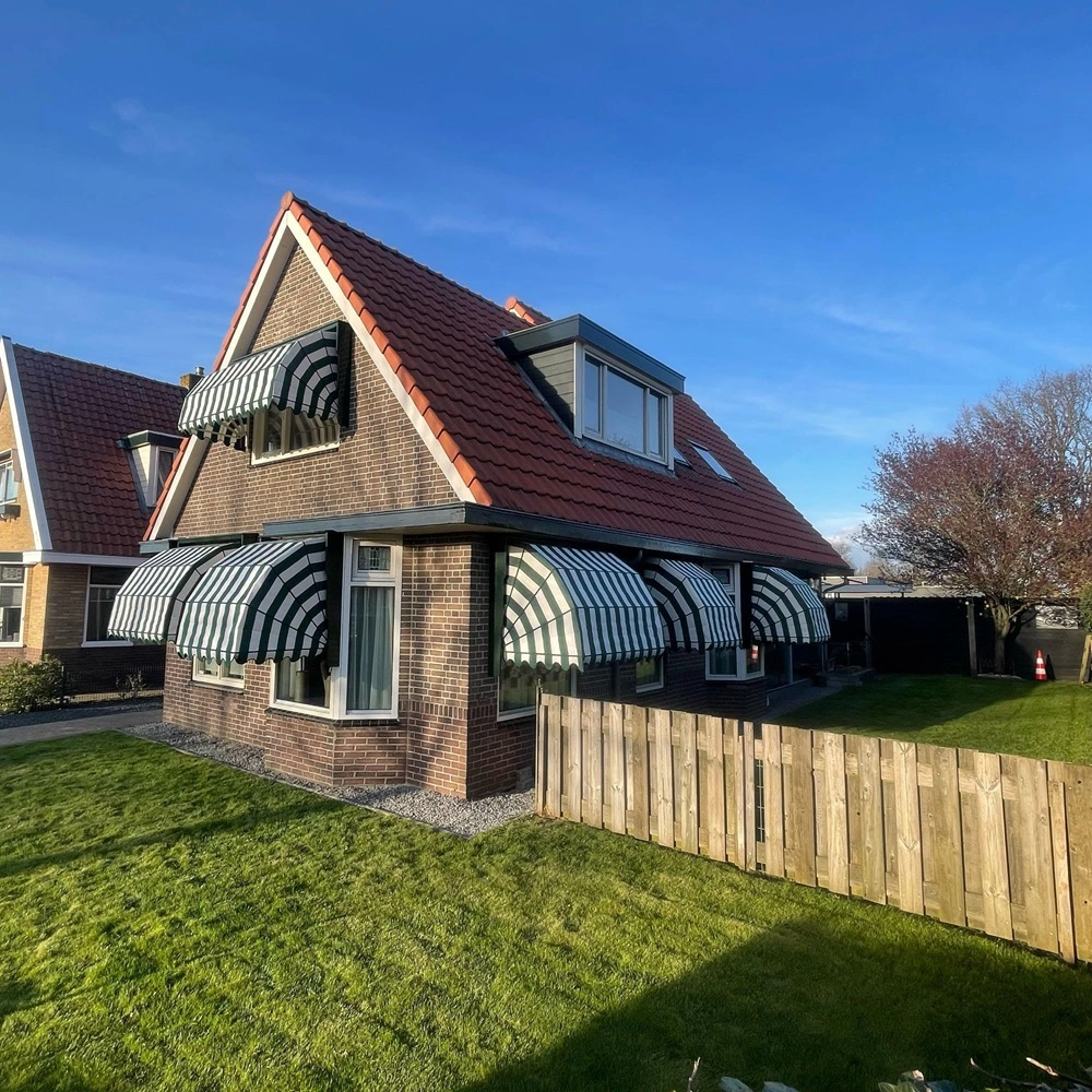 Bakstenen huis met groen-wit gestreepte aluminium markiezen rondom de ramen Bakstenen huis met groen-wit gestreepte aluminium markiezen rondom de ramen