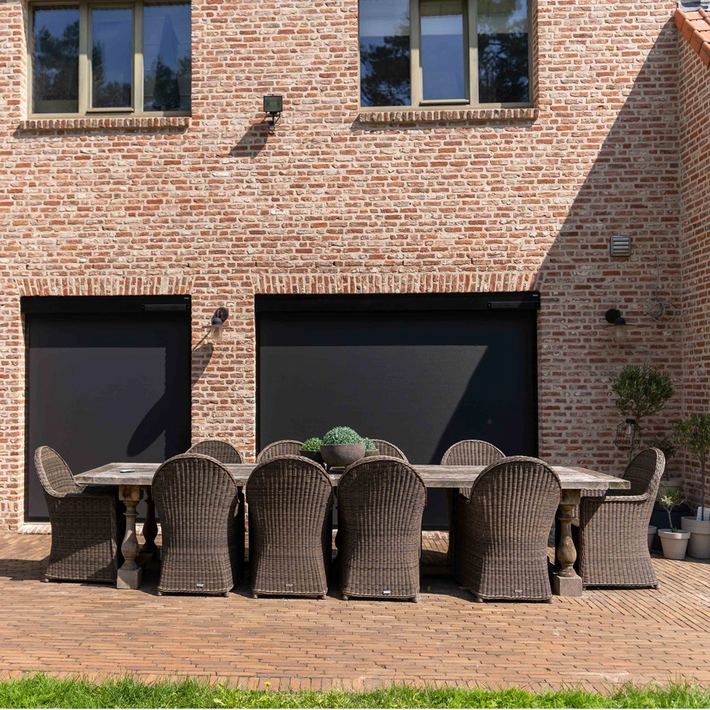 Cool screen Solar zonwering op terras met rieten stoelen tegen bakstenen muur