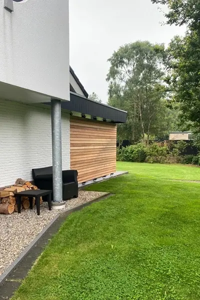 Gesloten lamellenwand van hout bij woning met overkapping en tuin Gesloten lamellenwand van hout bij woning met overkapping en tuin