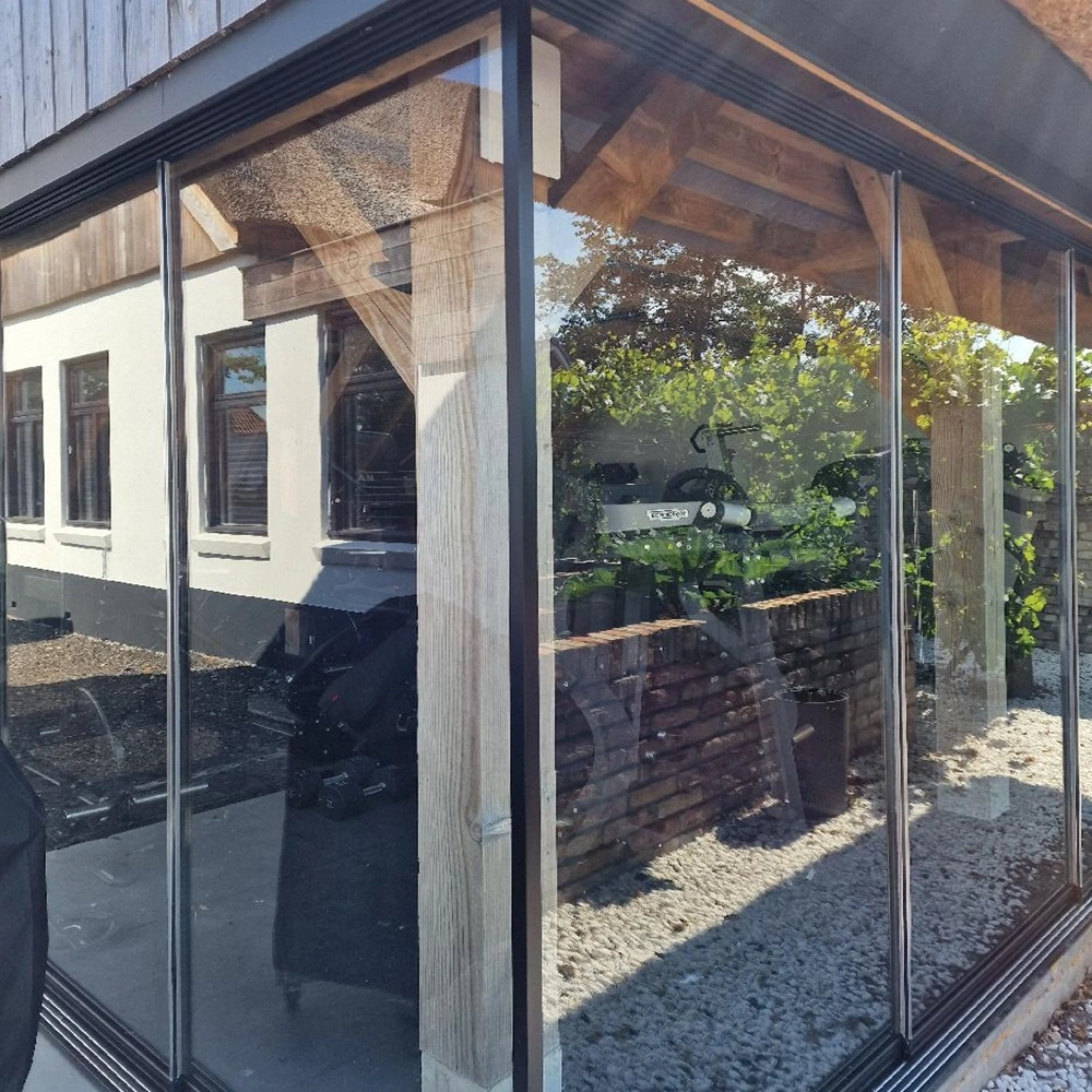 Glazen schuifwand in houten bijgebouw met zicht op fitnessapparatuur