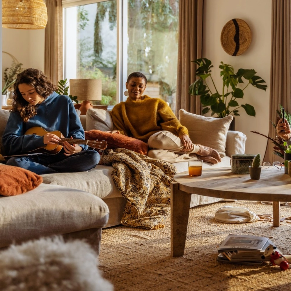 Groep vrienden geniet van slimme huisautomatisering via Tahoma box in de woonkamer