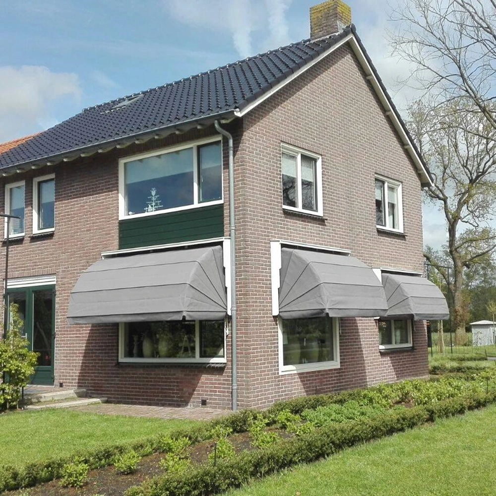 Houten markies in grijs boven ramen van een bakstenen huis met goed onderhouden tuin