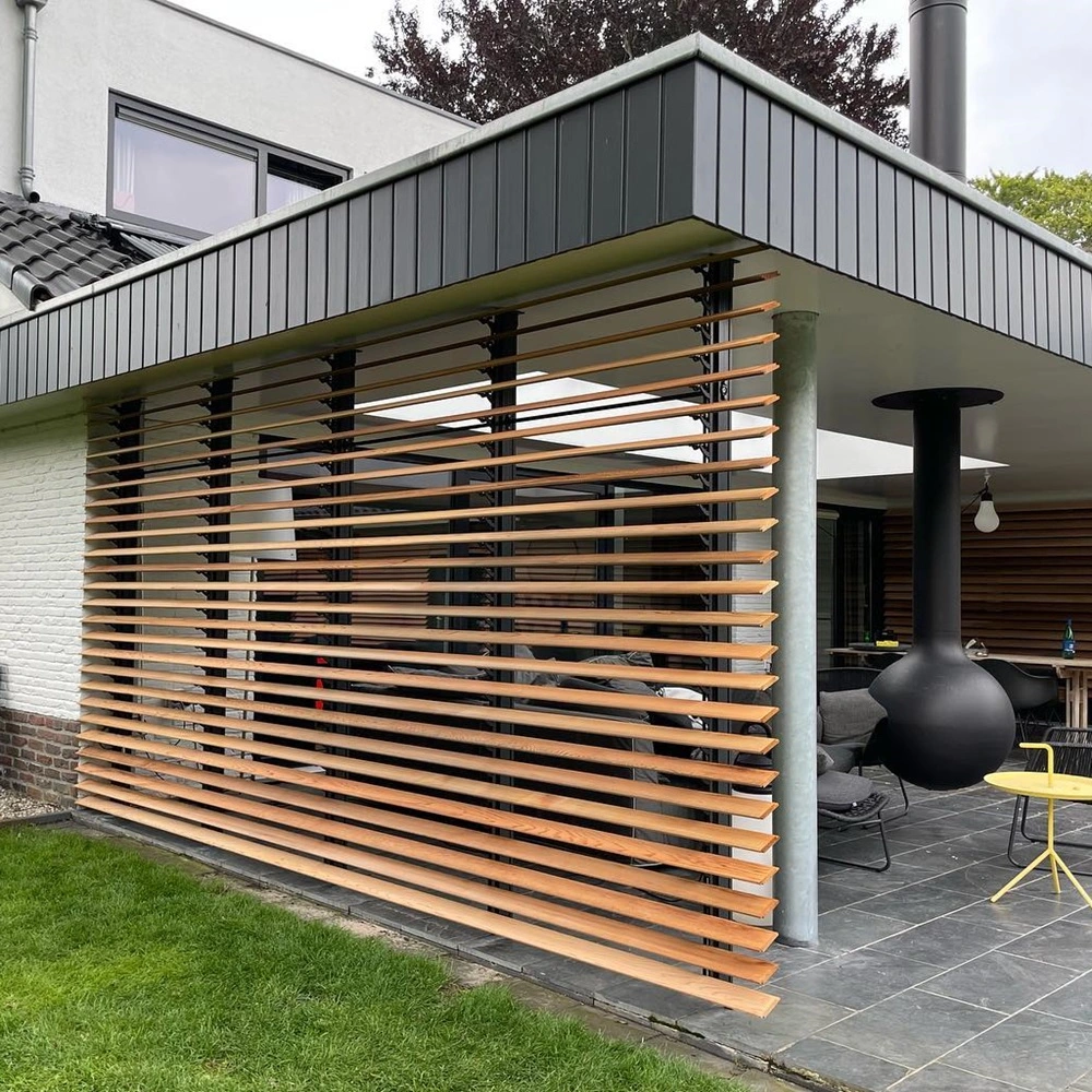 Lamellenwand van hout bij overdekt terras met zwarte hanghaard en tuinmeubilair