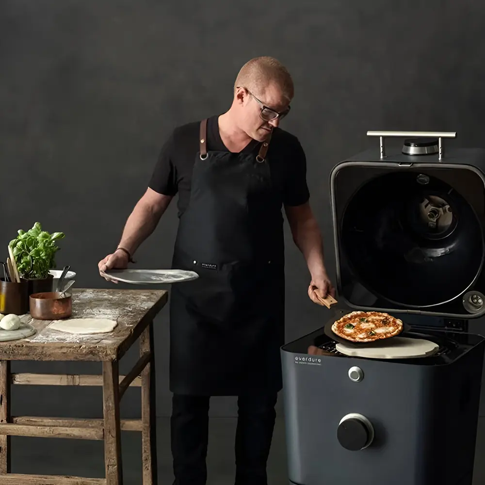 Man bakt pizza op Everdure houtskool BBQ