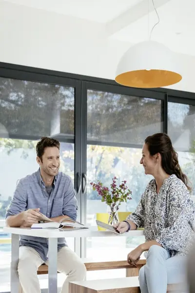 Man en vrouw zitten samen aan tafel met een Tahoma box met screens bij de ramen Man en vrouw zitten samen aan tafel met een Tahoma box met screens bij de ramen