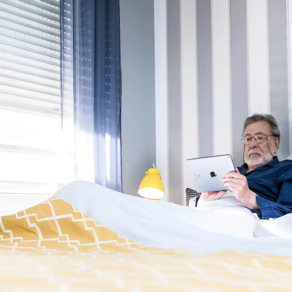 Man leest in bed met gesloten elektrische rolluiken voor comfort en privacy