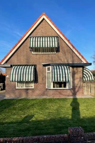 Markiezen woning met groen-witte gestreepte markiezen boven ramen Markiezen woning met groen-witte gestreepte markiezen boven ramen