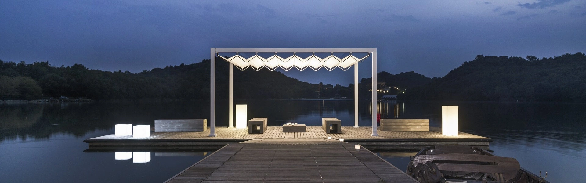 Overkapping Isola Fly verlicht op houten steiger bij avond