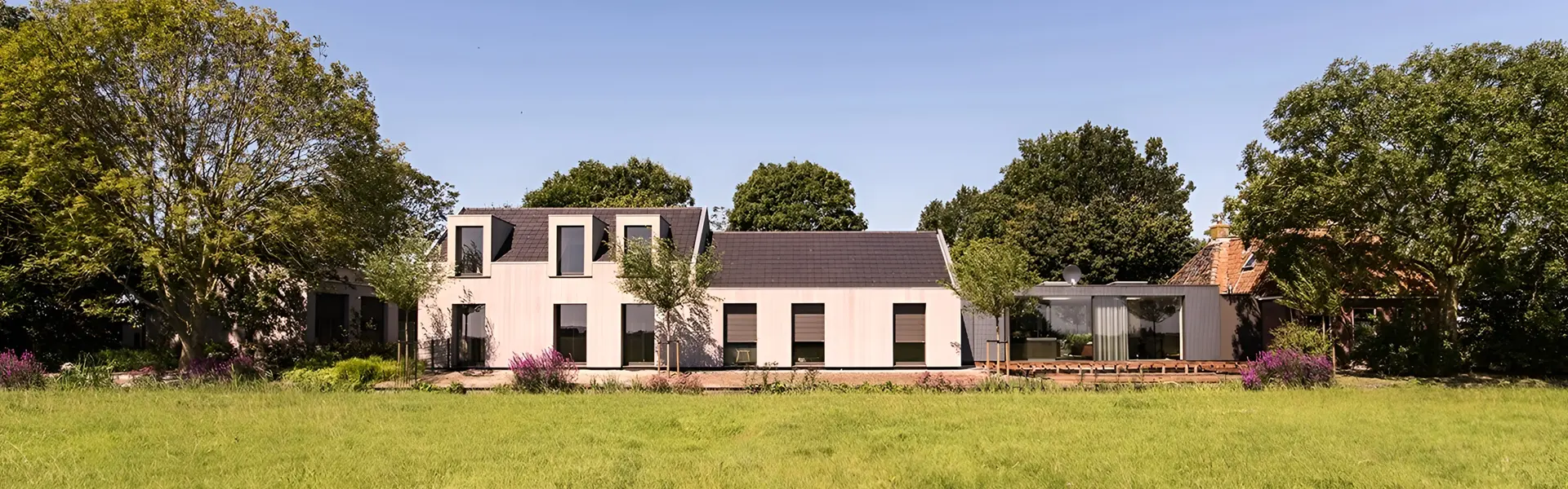 Rolluiken op landelijke woning met grote ramen en tuin, horizontaal geplaatst