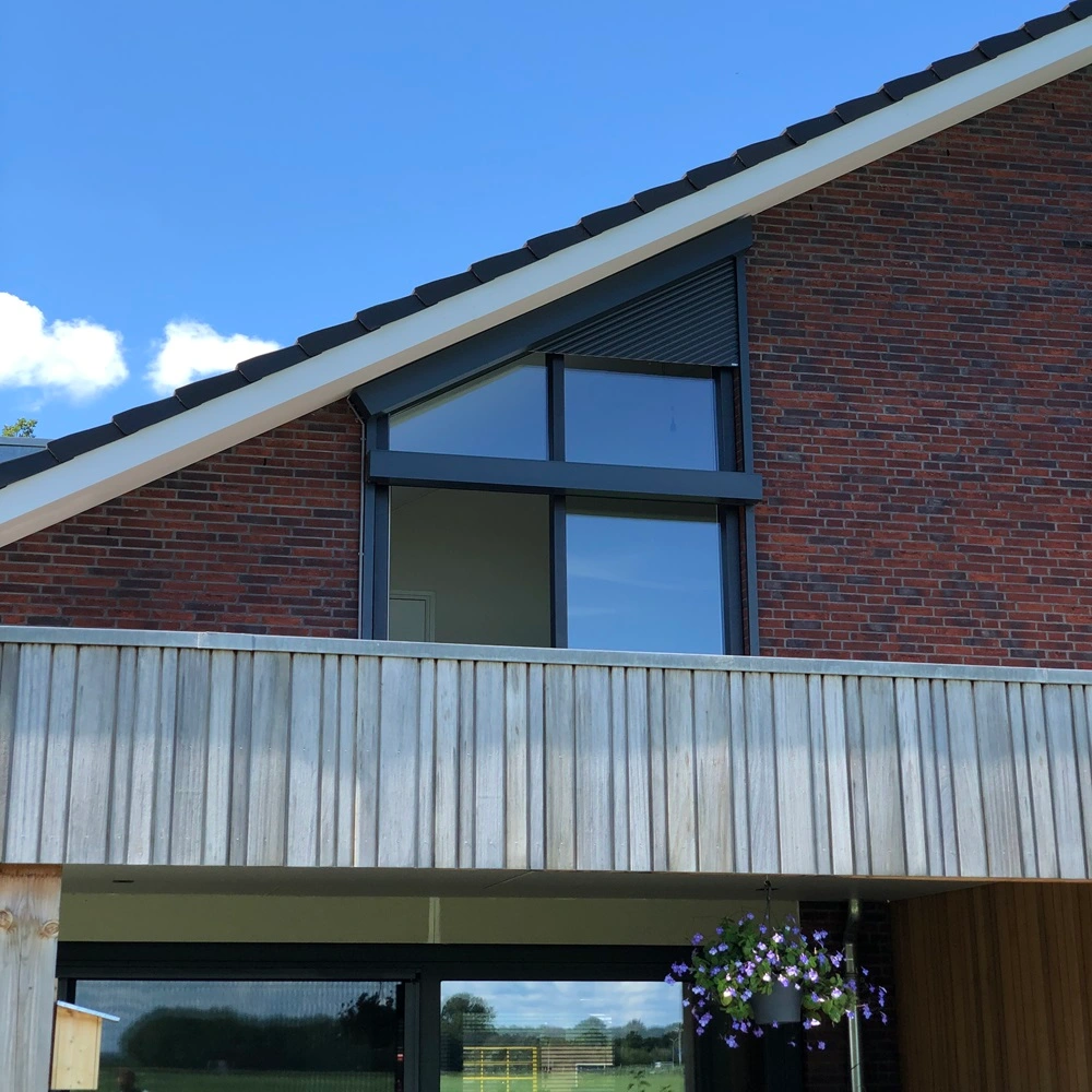 Roma rolluik op een schuin dak met grote glazen ramen en houten gevelbekleding