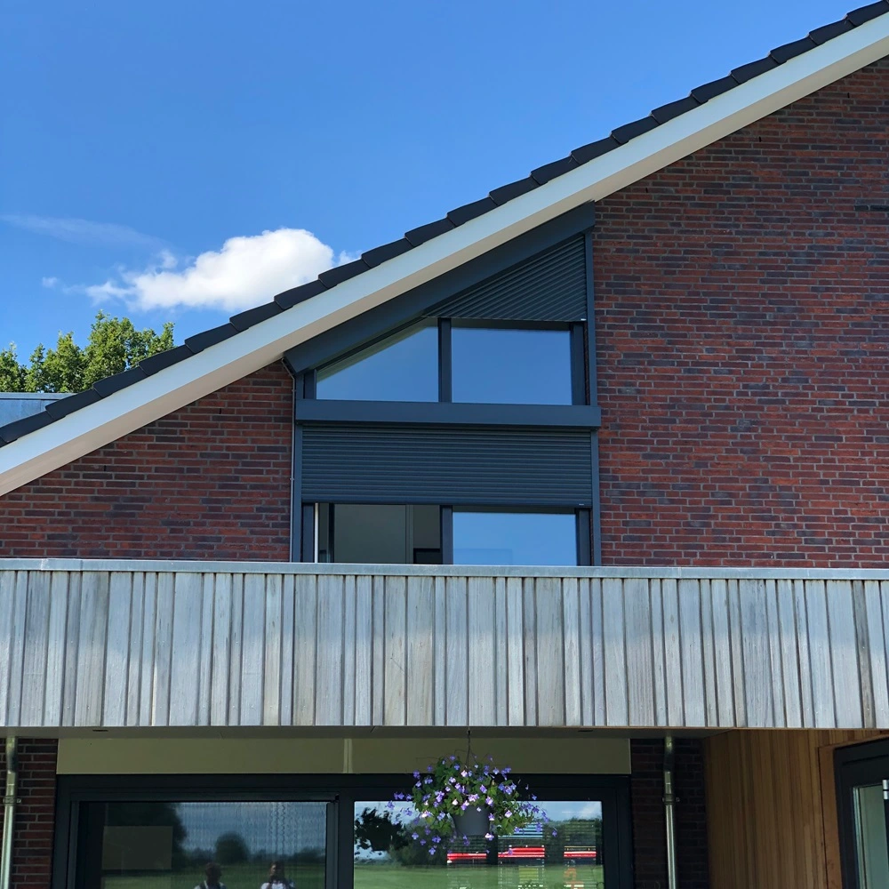 Roma rolluik op een schuine dakgevel van een bakstenen huis