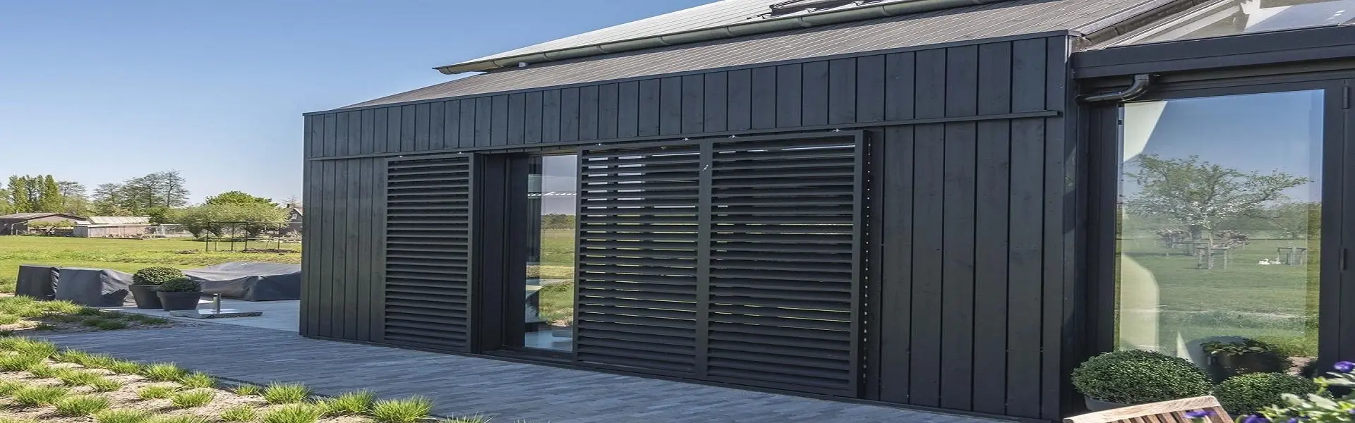 Schuifluiken op zwarte houten gevel, ontworpen voor schaduw en privacy