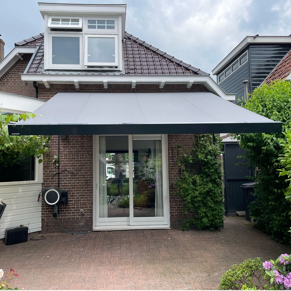 Uitgeschoven zonnescherm op terras bij huis met bakstenen gevel