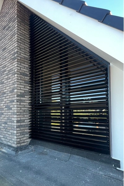 Vaste lamellen op een schuine gevel bij raam voor schaduw en privacy Vaste lamellen op een schuine gevel bij raam voor schaduw en privacy