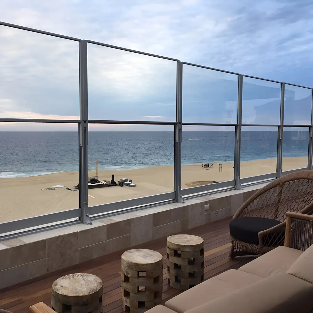 Windscherm Habitat Win op terras met houten meubels en uitzicht op een rustig strand