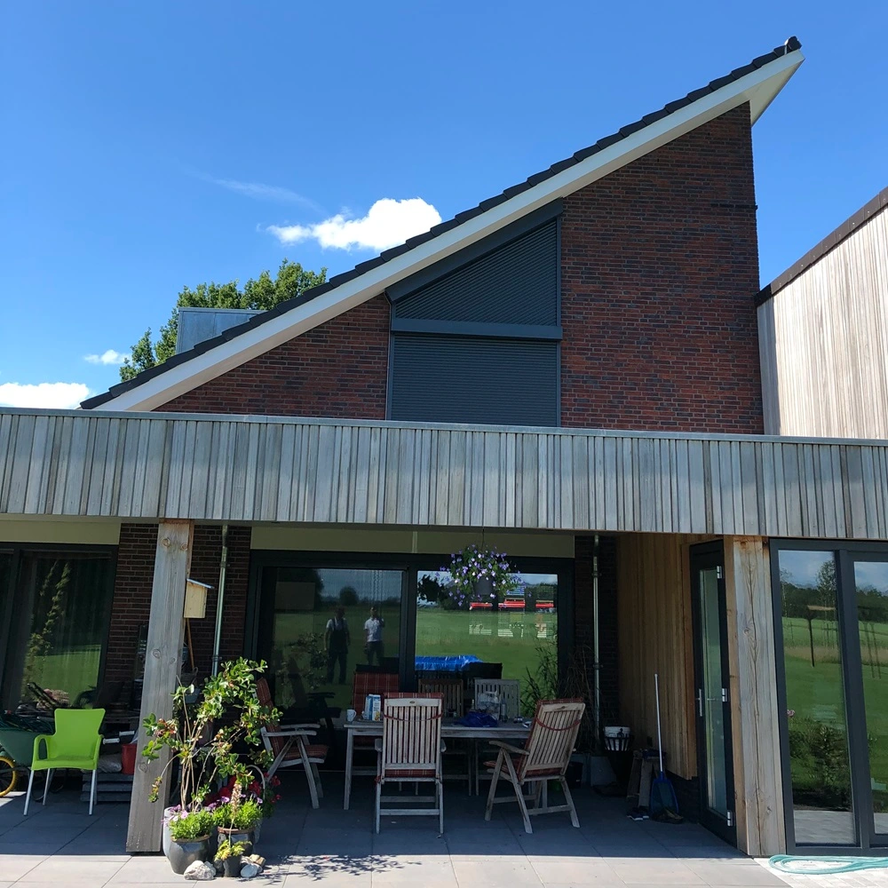 Woning met Roma rolluik op schuine daklijn, houten terras en grote ramen