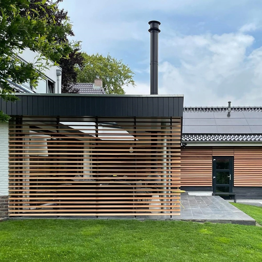 Zijaanzicht van terras met houten lamellenwand en groene grasveld