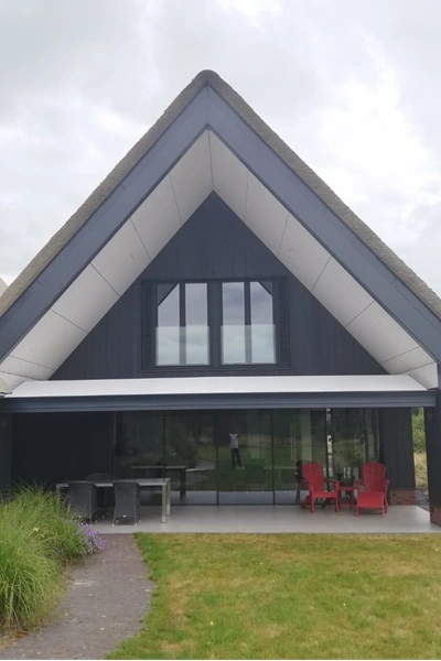 Zon en regenscherm autovolant aan woning met overkapping en terrasstoelen Zon en regenscherm autovolant aan woning met overkapping en terrasstoelen