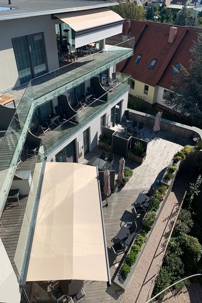 Zon en regenscherm type L boven terras met glazen balkon en zitplaatsen Zon en regenscherm type L boven terras met glazen balkon en zitplaatsen
