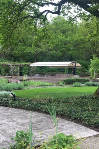 Zon en regenwering bij vijver in groene tuin Zon en regenwering bij vijver in groene tuin