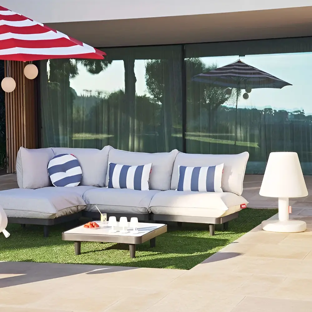 Fatboy Edison lamp en bolleke bij loungeset met rode parasol op terras